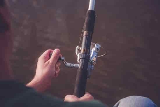 canva fisherman with fishing rod on the river bank close up MADapgMUHC0