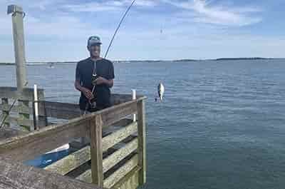 man on pier fishing caught a small fish
