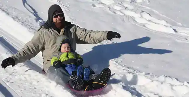 man and young son sledding