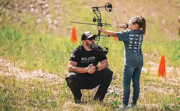 beginner archery young girl with teacher practicing pulling and aiming