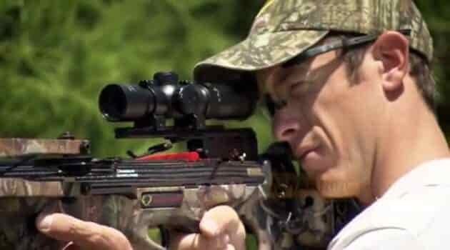 man fireing crossbow with scope