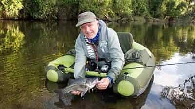 fisherman in float tube showing trout catch