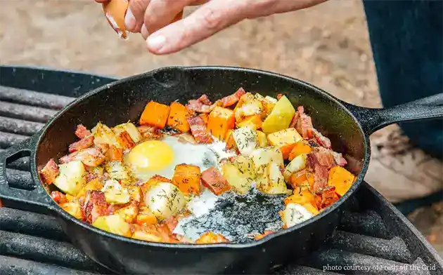cooking on portable grill sausage eggs potatoes carrots and onion