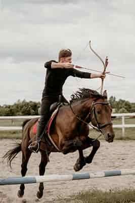 man on horse jumping competition shooting bow and arrow like the American Indians use to do
