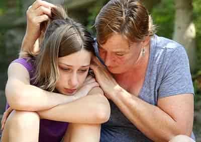 Older woman talking with younger woman with sad expressions on their respective faces