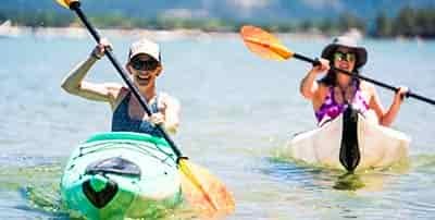 two kayaking women having fun smiling while paddling