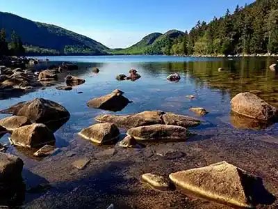 brook entering lake with rocks along shoreline making its way through mountains