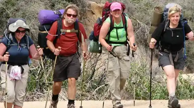 4 people hiking with back packs and hiking canes
